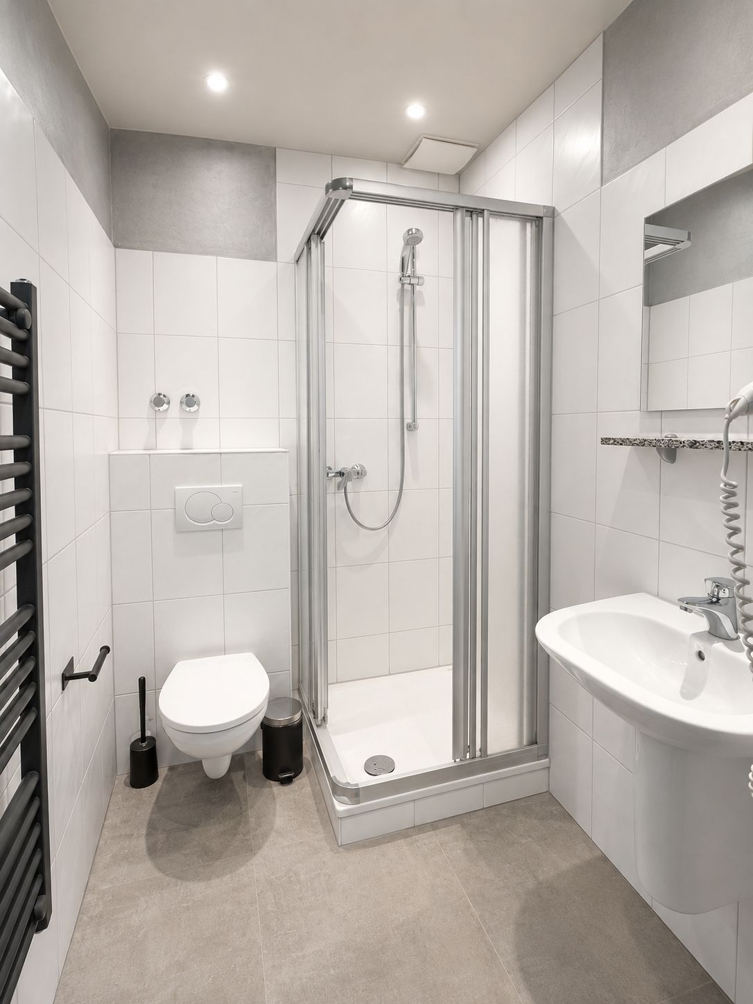 Et moderne badeværelse med en brusekabine med glasvægge, toilet og håndvask.