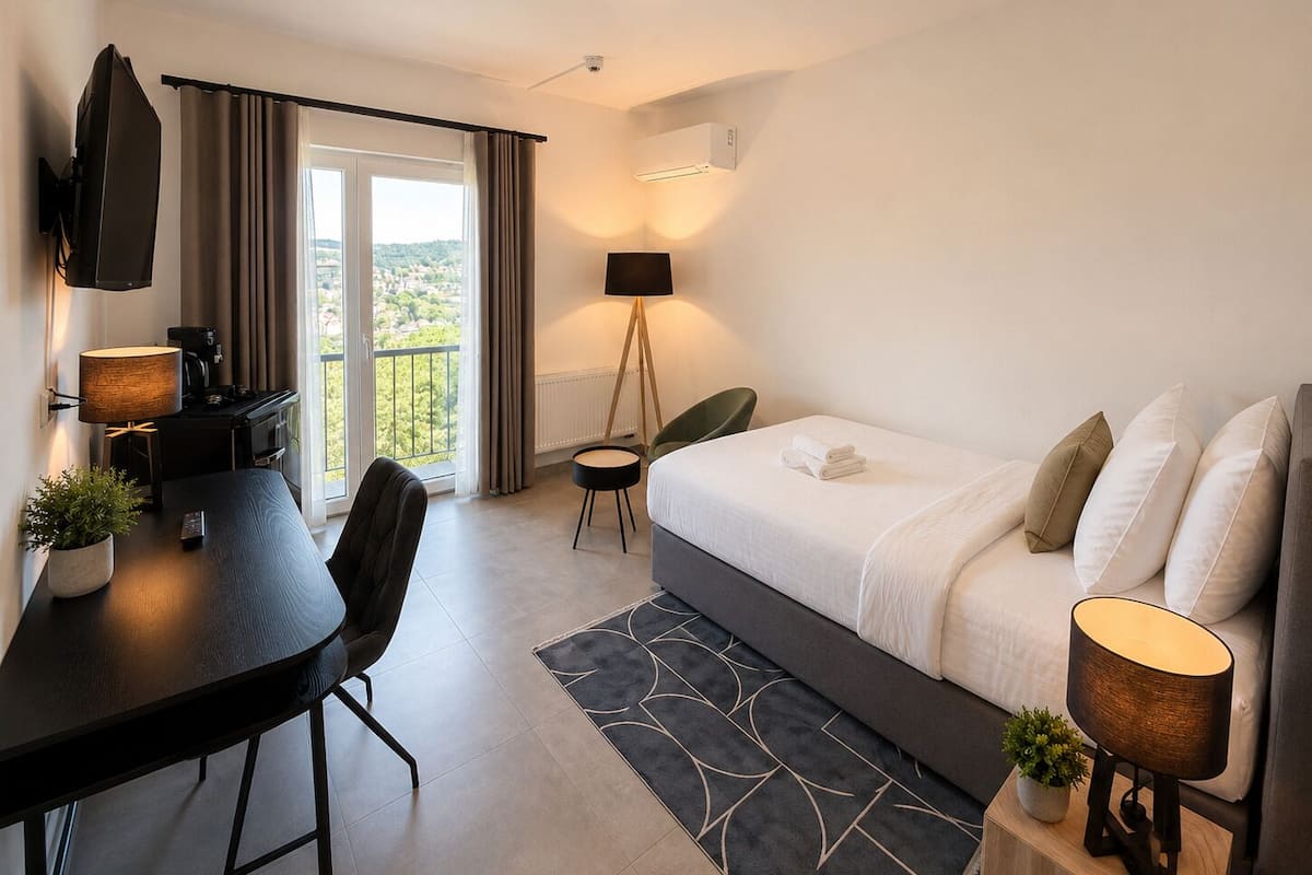 Une chambre d’hôtel équipée d’un lit, d’un bureau, d’une chaise, d’une télévision, d’une lampe et offrant une vue sur l’extérieur.