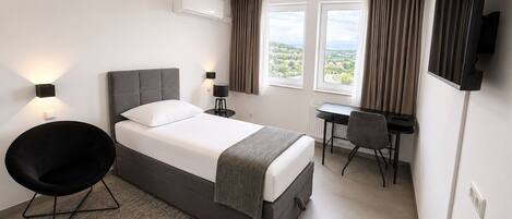 Una habitación de hotel moderna con cama, escritorio, silla y televisor.