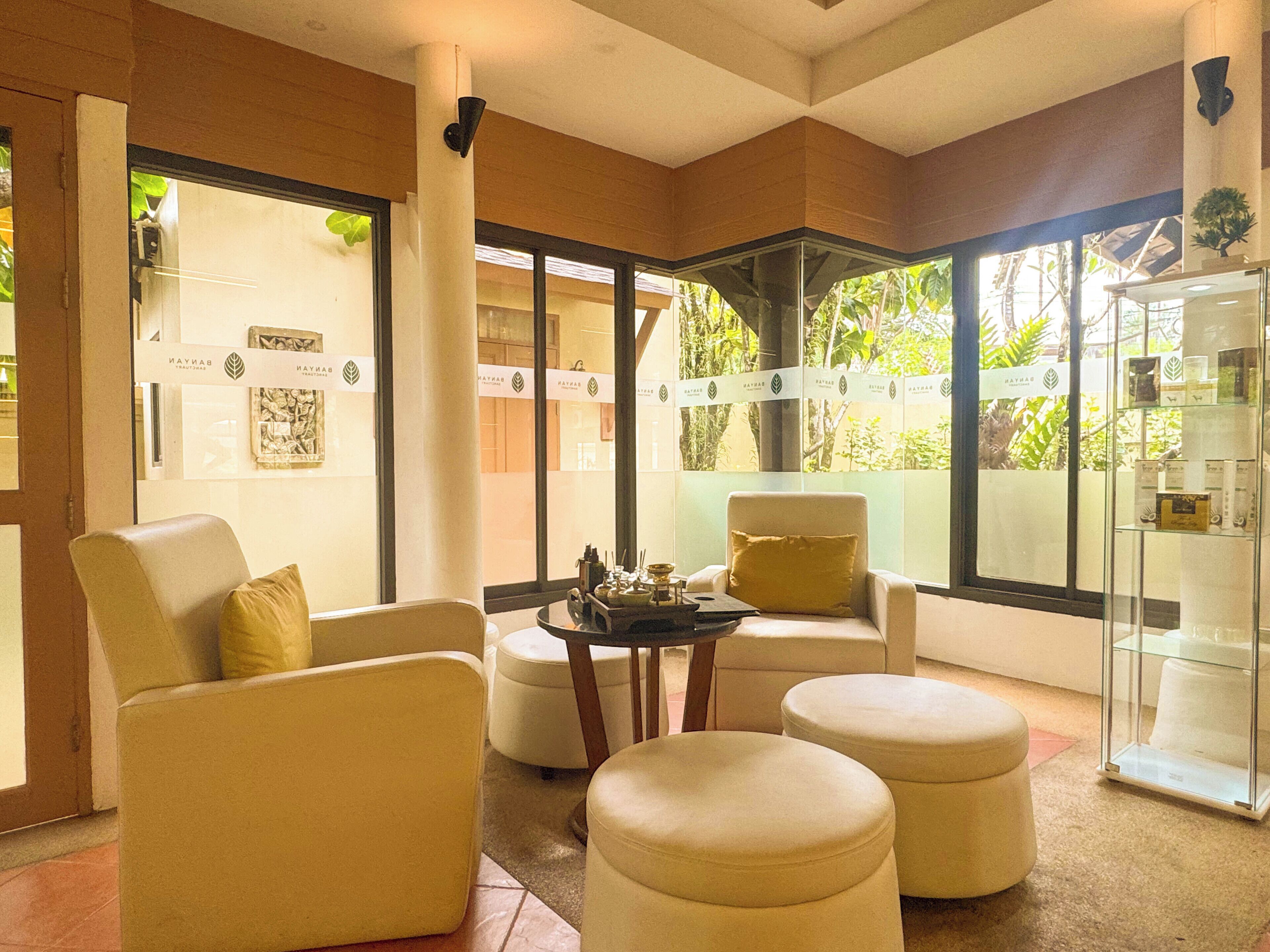 Un intérieur moderne avec un espace salon comprenant un canapé et des poufs, une vitrine et une vue sur la verdure à l’extérieur.