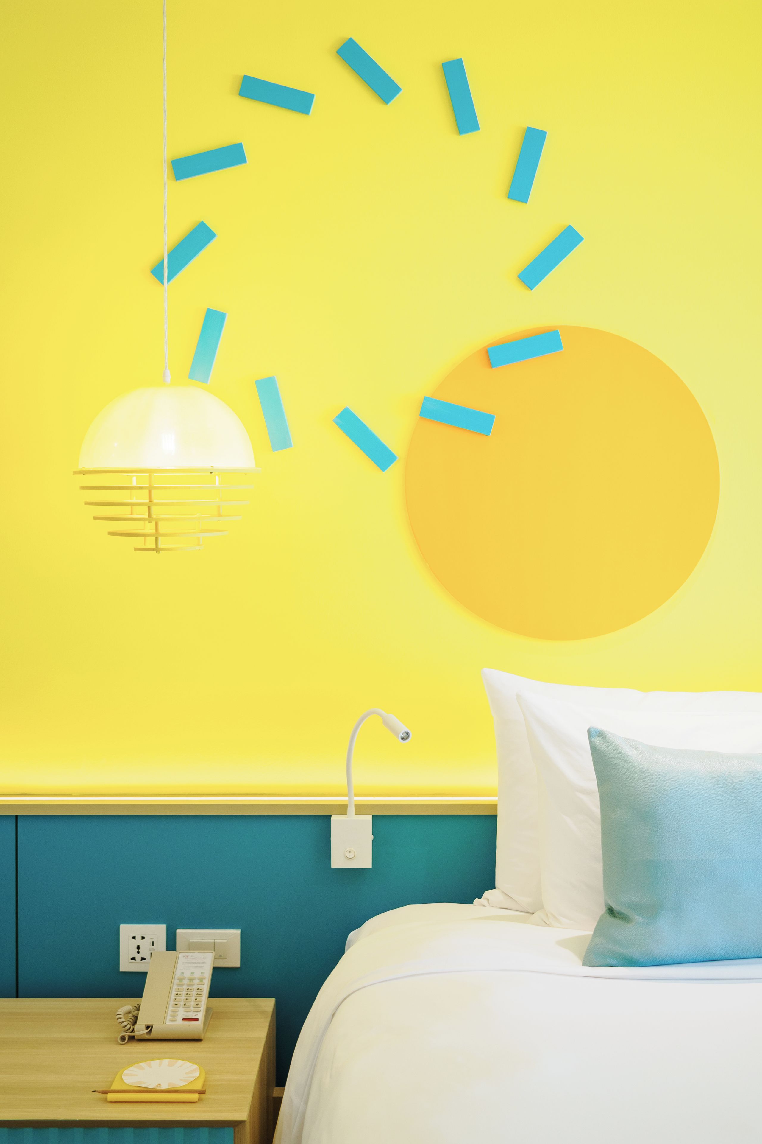 A room with a bed, a nightstand with a phone, and a wall clock.