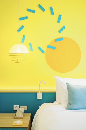 Een kamer met een bed, een nachtkastje met een telefoon en een wandklok.