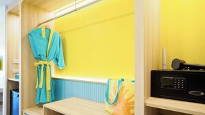 Une salle de bain avec un meuble-lavabo en bois, un porte-serviettes avec un peignoir, une poubelle et un four à micro-ondes.