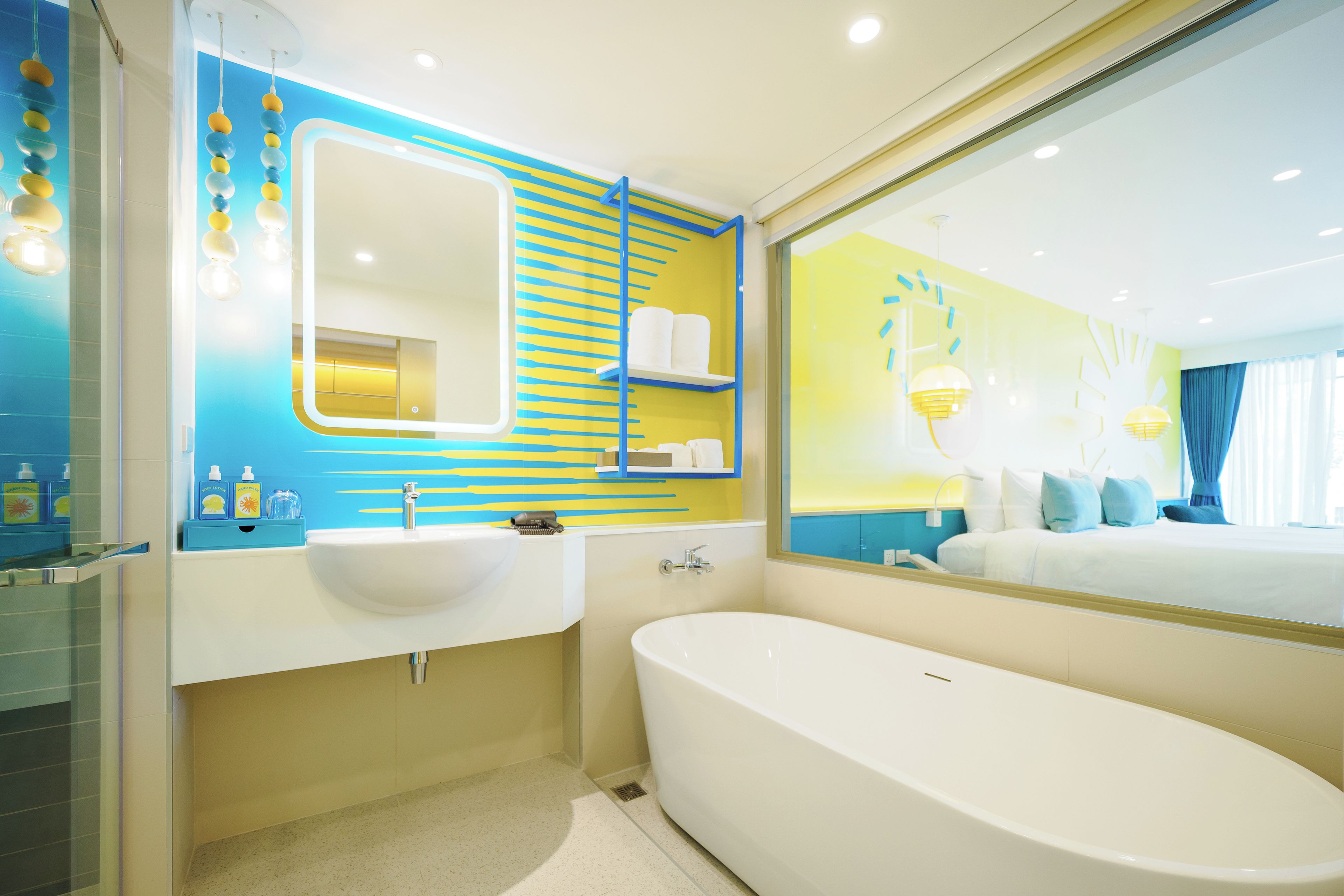 A modern bathroom with a large bathtub, a double sink, and a mirror with a blue frame.