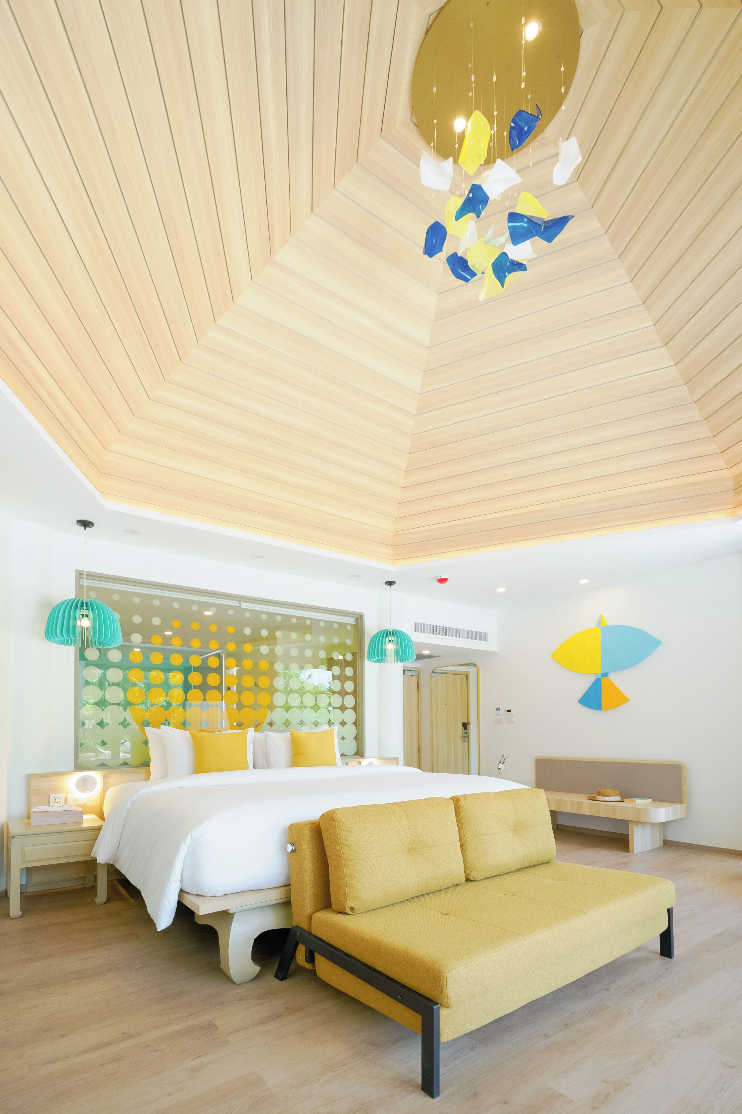 A modern bedroom with a bed, a sofa, a wooden ceiling, and a wall with circular patterns.