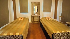 Une chambre avec deux lits, un miroir, une petite table et une chaise.
