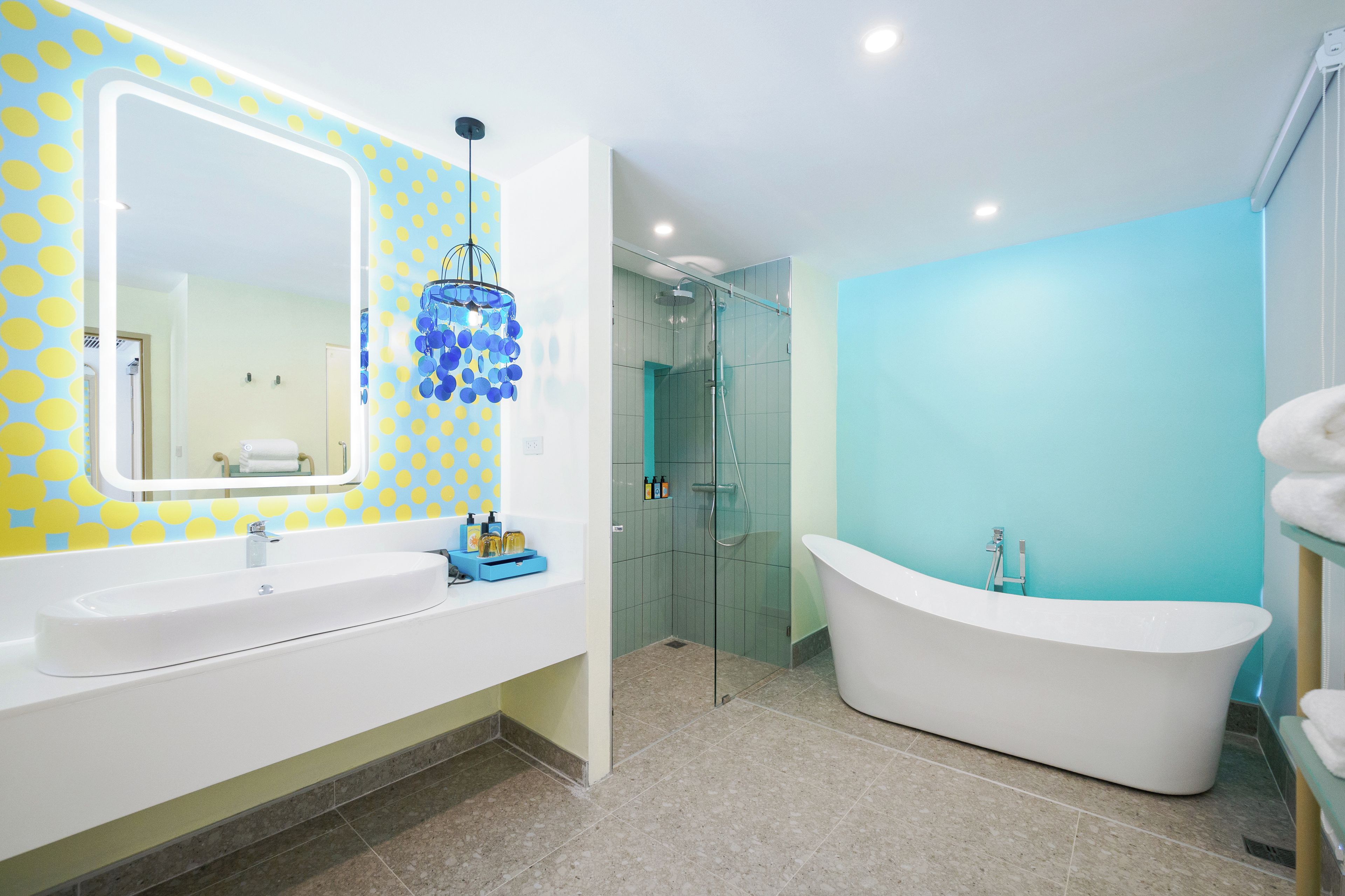 Un baño moderno con un espejo grande, dos lavamanos, una bañera independiente y una ducha con paredes de vidrio.
