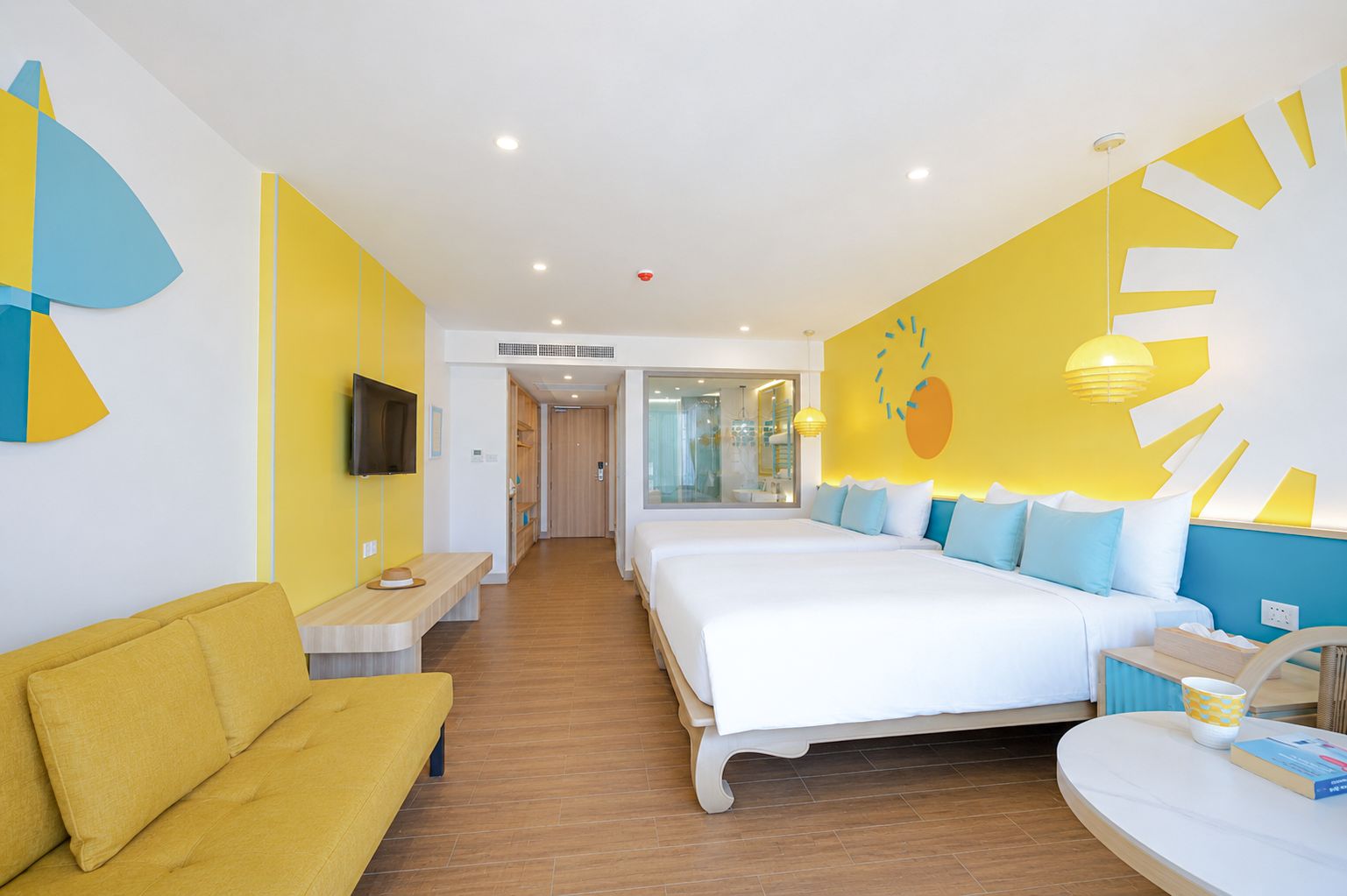 Habitación de hotel con una cama grande, un sofá, un televisor y una pared con un diseño de frutas.