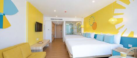 Habitación de hotel con una cama grande, un sofá, un televisor y una pared con un diseño de frutas.