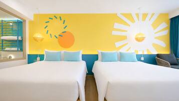 Habitación de hotel con dos camas, un gran mural con motivos de sol y vistas al mar.