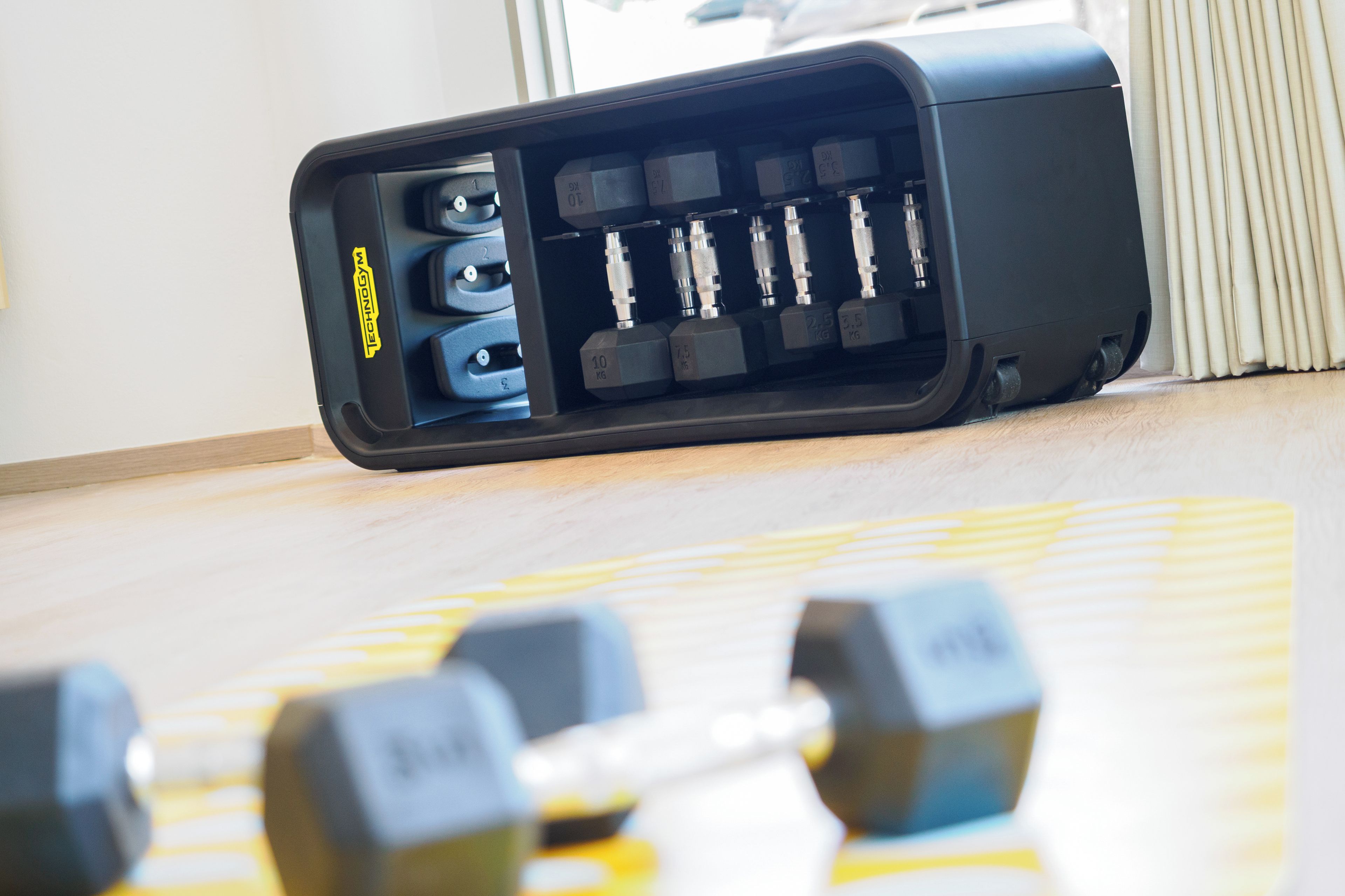 A black electronic device with multiple ports and a label 'TECHNOLOGY' on it, placed on a wooden floor.