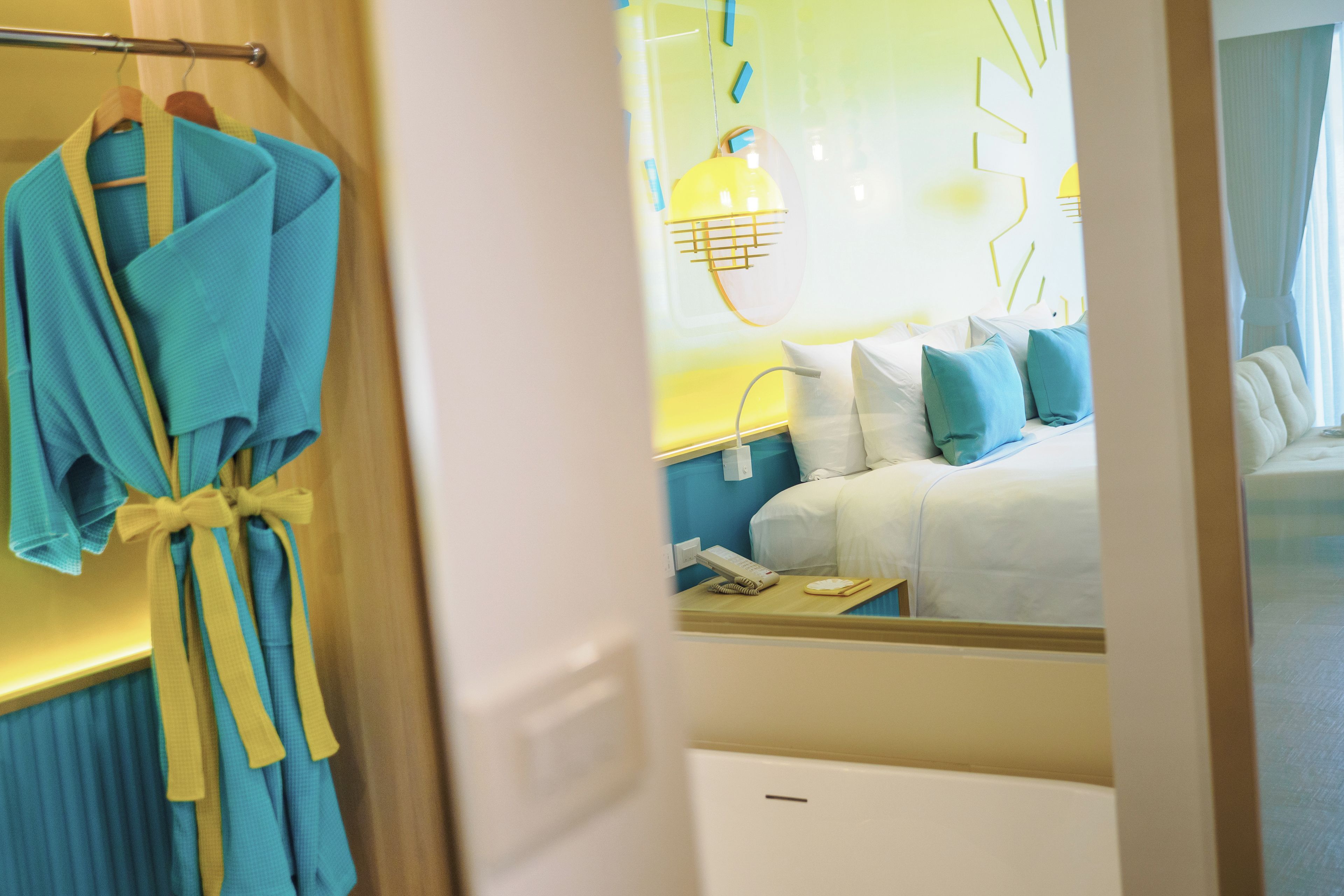 Une chambre d’hôtel avec un lit, une table de chevet, une lampe et un peignoir suspendu à un porte-manteau.
