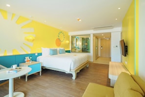 Habitación de hotel con cama, escritorio, silla, televisión y baño visible a través de una puerta abierta.