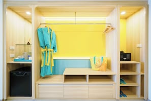 Una habitación compacta con una banca, una bata, un bolso y un estante con zapatillas.