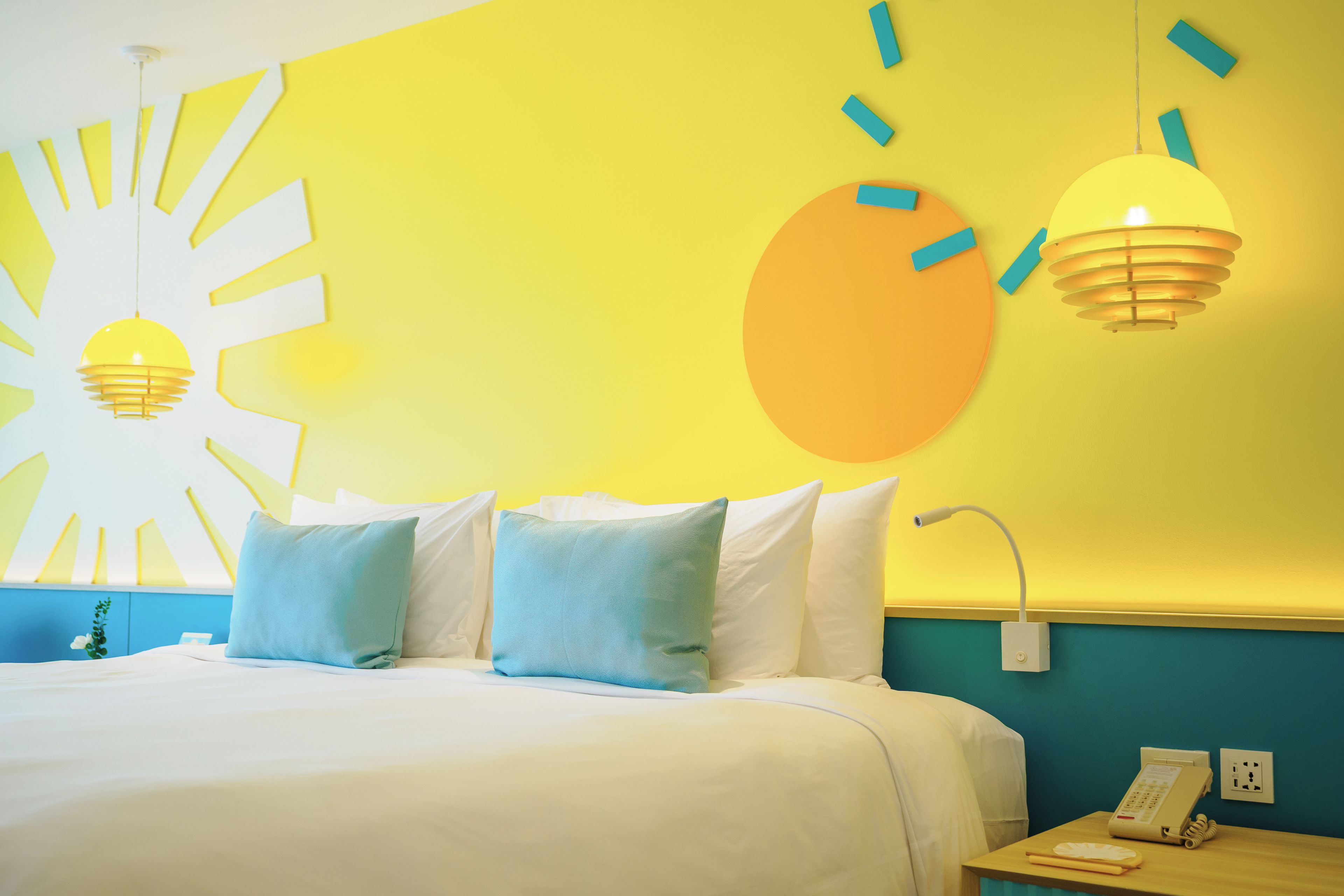Une chambre d’hôtel avec un lit, des oreillers, une table de chevet, un téléphone et des œuvres d’art murales.