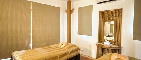 Una habitación de hotel con dos camas, un baño con espejo y lavamanos, y un ventanal grande con cortinas.
