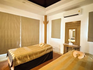 Hotelkamer met twee bedden, een badkamer met spiegel en wastafel, en een groot raam met gordijnen.