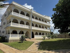 A multi-story building with a symmetrical facade, multiple balconies, and a central entrance.