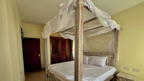 Un letto a baldacchino con tende, un comodino in legno e un armadio con specchio.