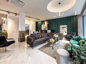 A modern living room with a sofa, armchairs, a coffee table, and a reception desk.