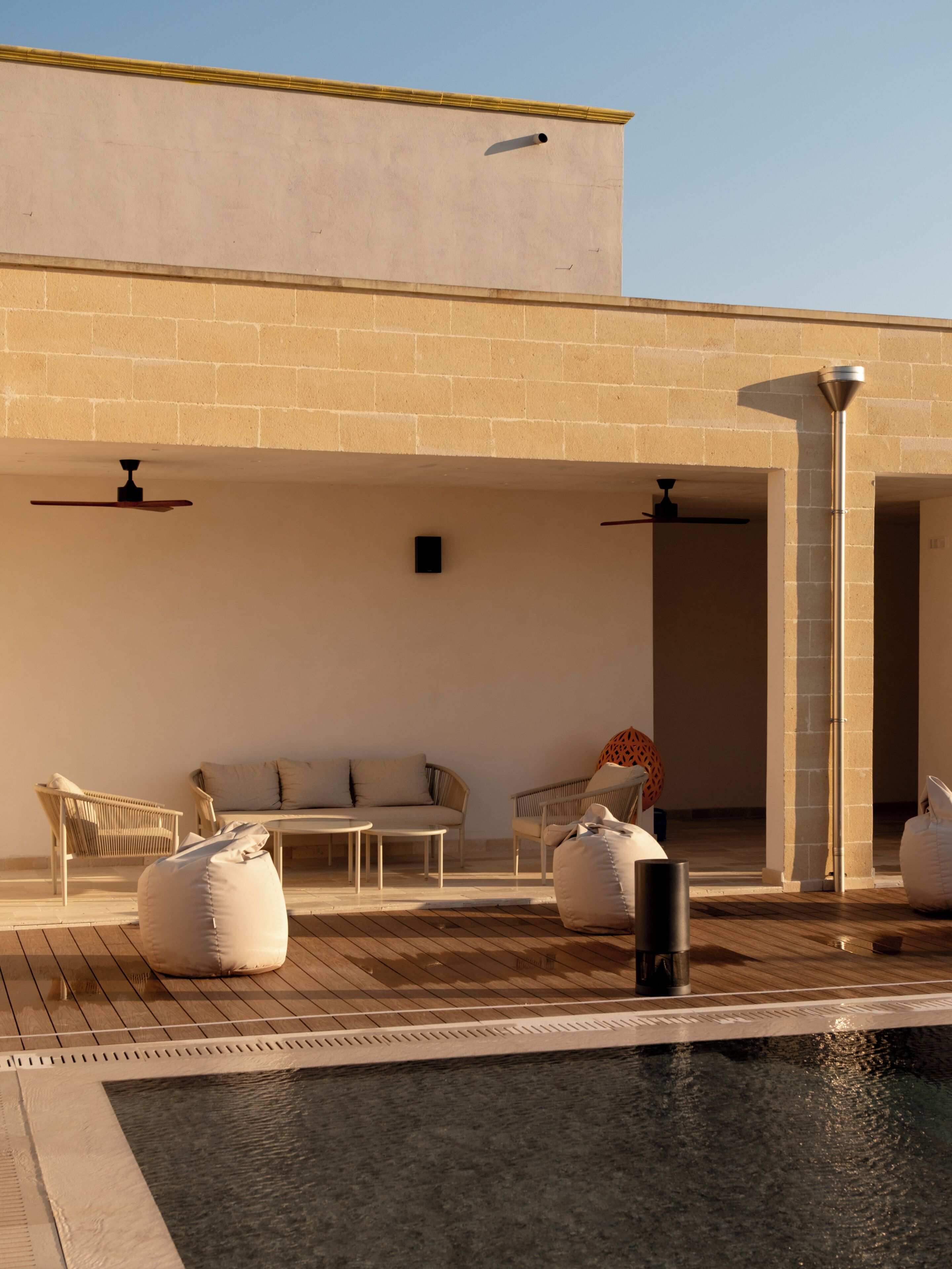 A poolside area with outdoor seating, a water feature, and a building facade.