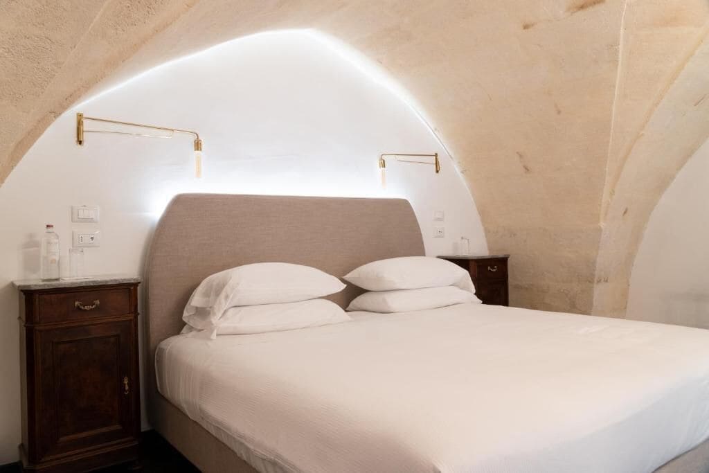 Une chambre à coucher avec un lit, une table de chevet et une lampe fixée au mur.