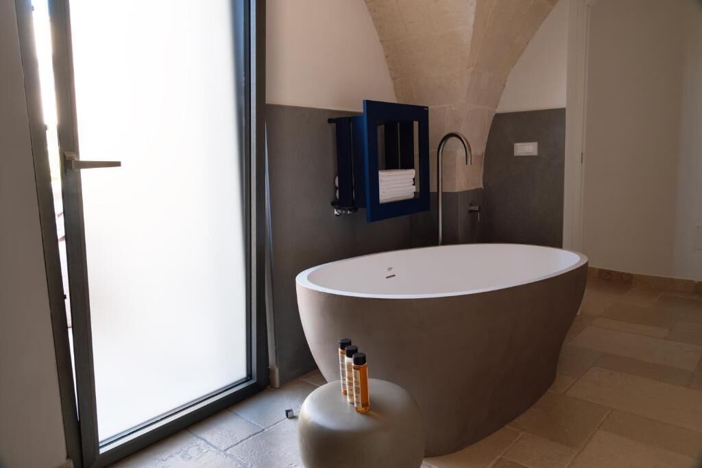 Un bagno moderno con una vasca da bagno ovale grande, uno spazio doccia in vetro e un porta asciugamani.