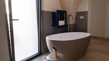 Un bagno moderno con una vasca da bagno ovale grande, uno spazio doccia in vetro e un porta asciugamani.
