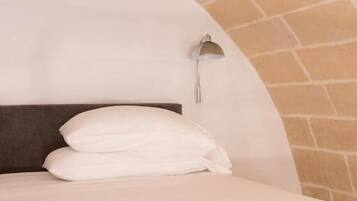 A bed with a headboard, a wall-mounted light fixture, and a brick ceiling.
