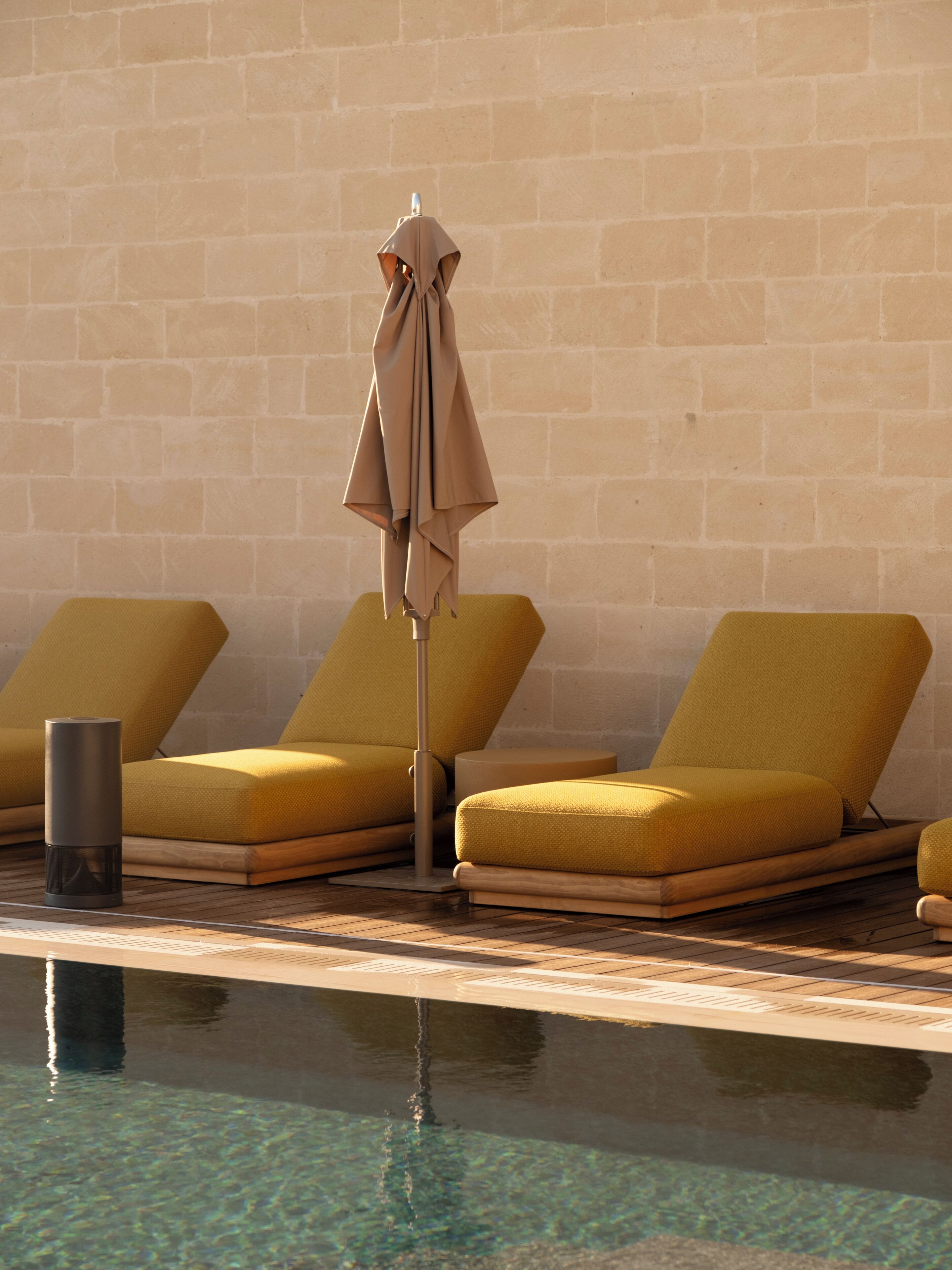 A poolside area with lounge chairs and a table, a brick wall in the background, and a clear pool.