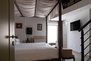 Un dormitorio con cama, una silla, un televisor montado en la pared y una escalera.