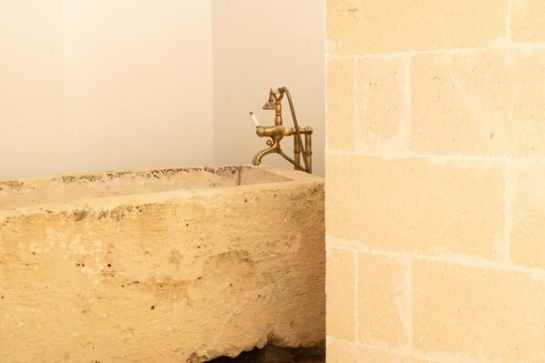 Une salle de bain avec un lavabo en pierre et un robinet en laiton.