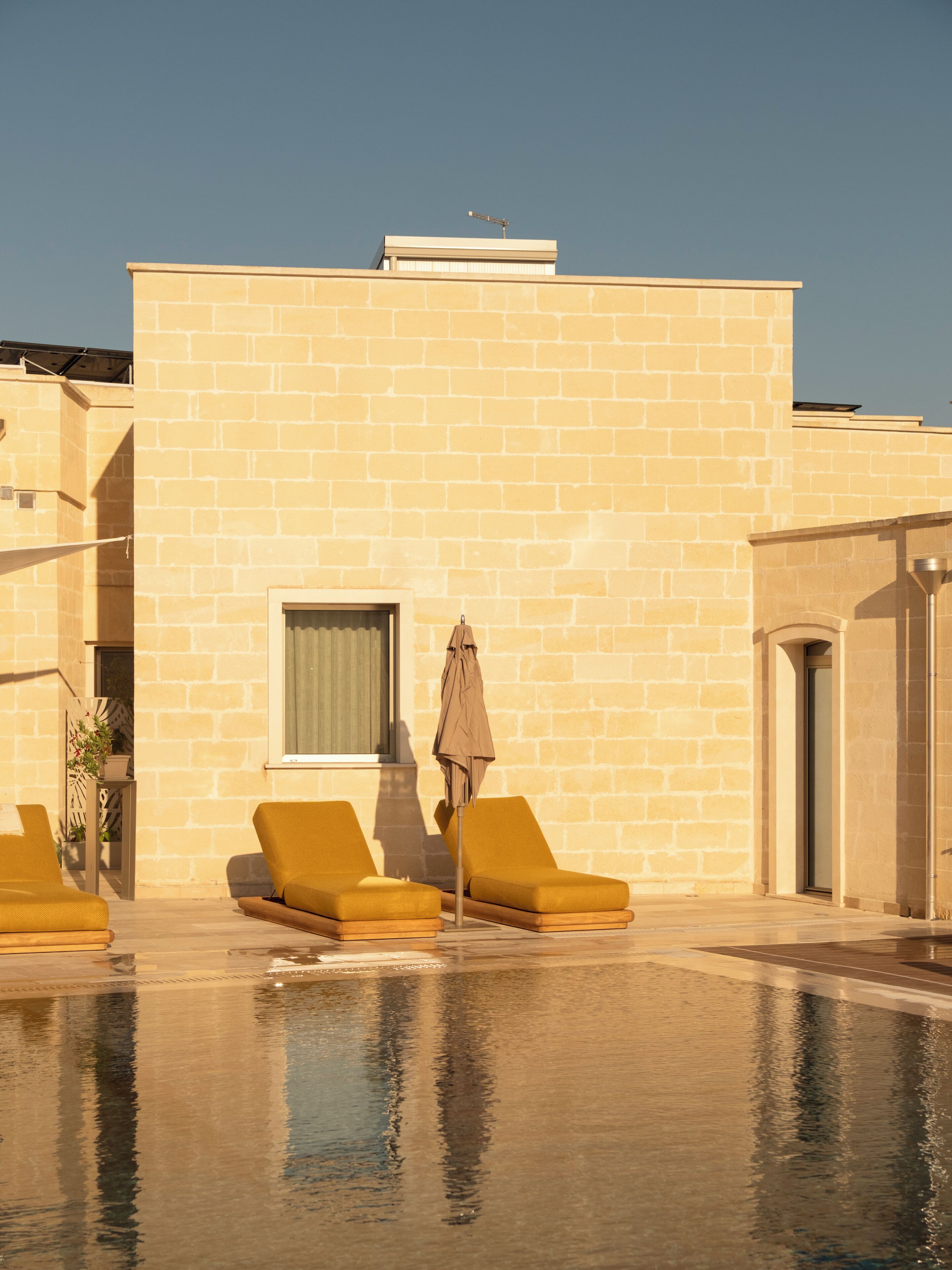 A pool area with two sun loungers and a single umbrella.