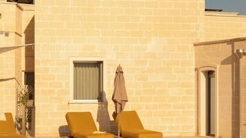 A pool area with two sun loungers and a single umbrella.