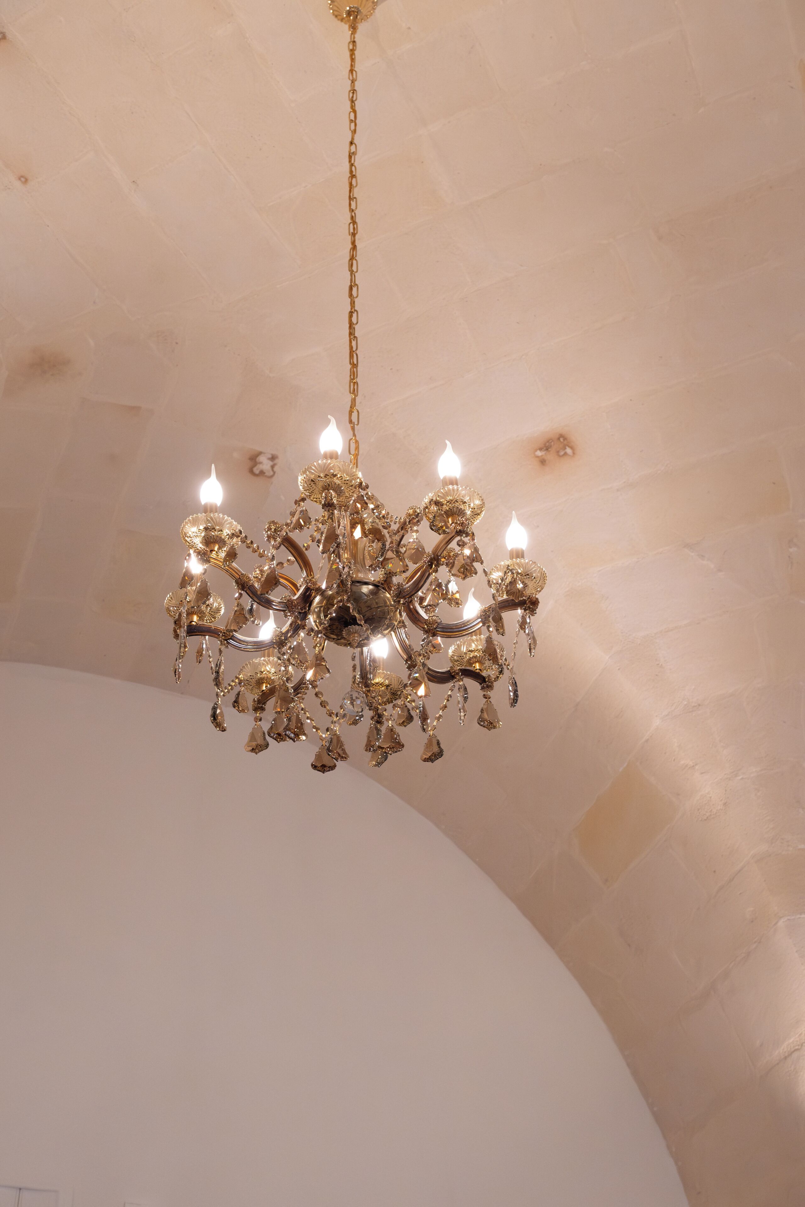 A chandelier with multiple candle-like lights hanging from a chain.
