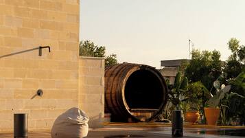 Piscina com um barril, parede bege e plantas em vasos.