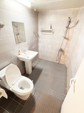 A bathroom with a toilet, sink, mirror, shower, and tiled walls. - Hotel Amy (Incheon)