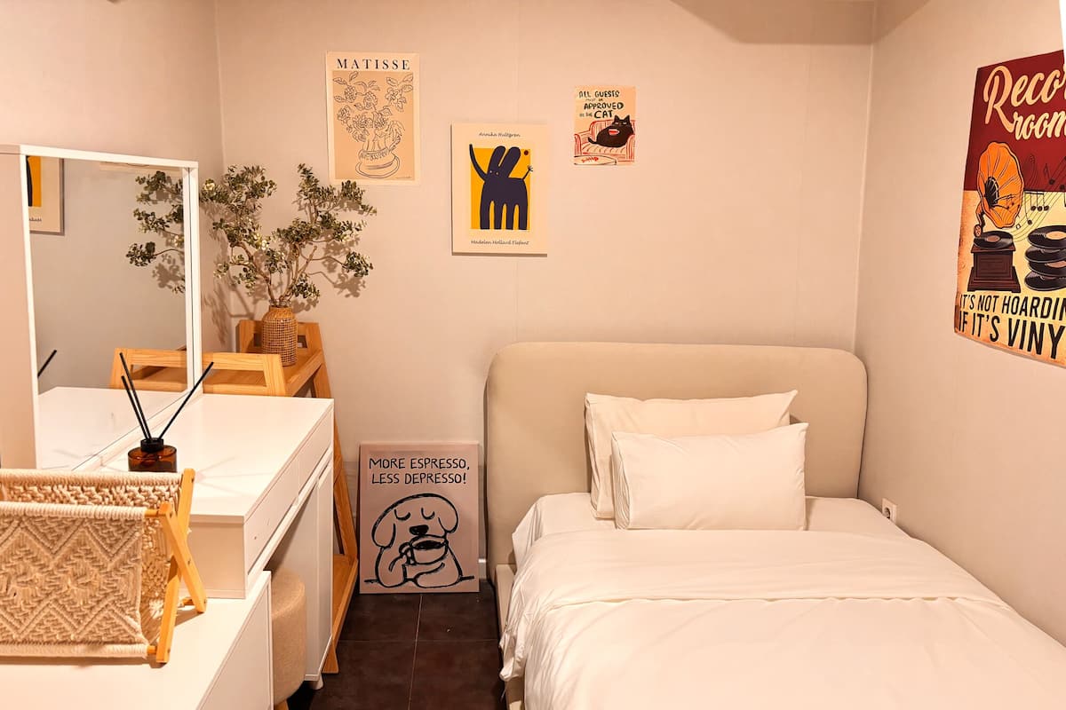 Ein Schlafzimmer mit Bett, Kommode, Spiegel und Wandbildern.