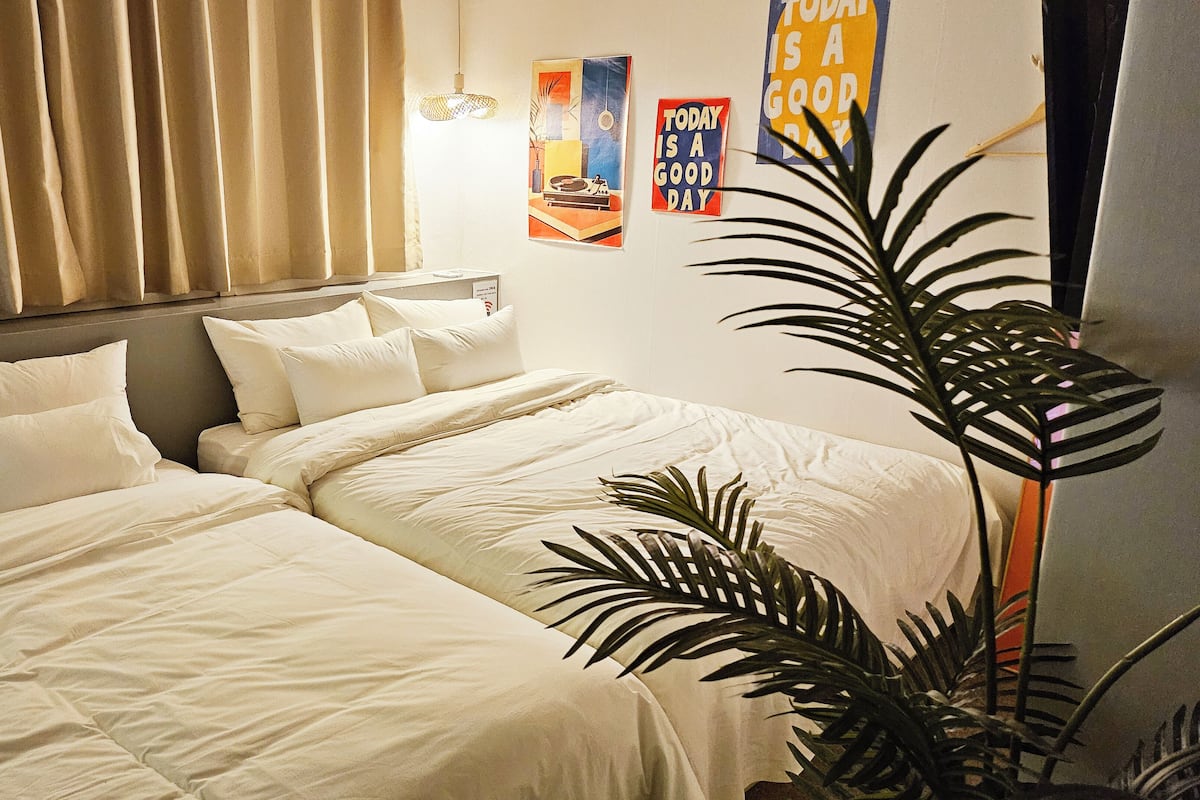 Ein Hotelzimmer mit zwei Betten, einer Topfpflanze und motivierenden Postern an der Wand.