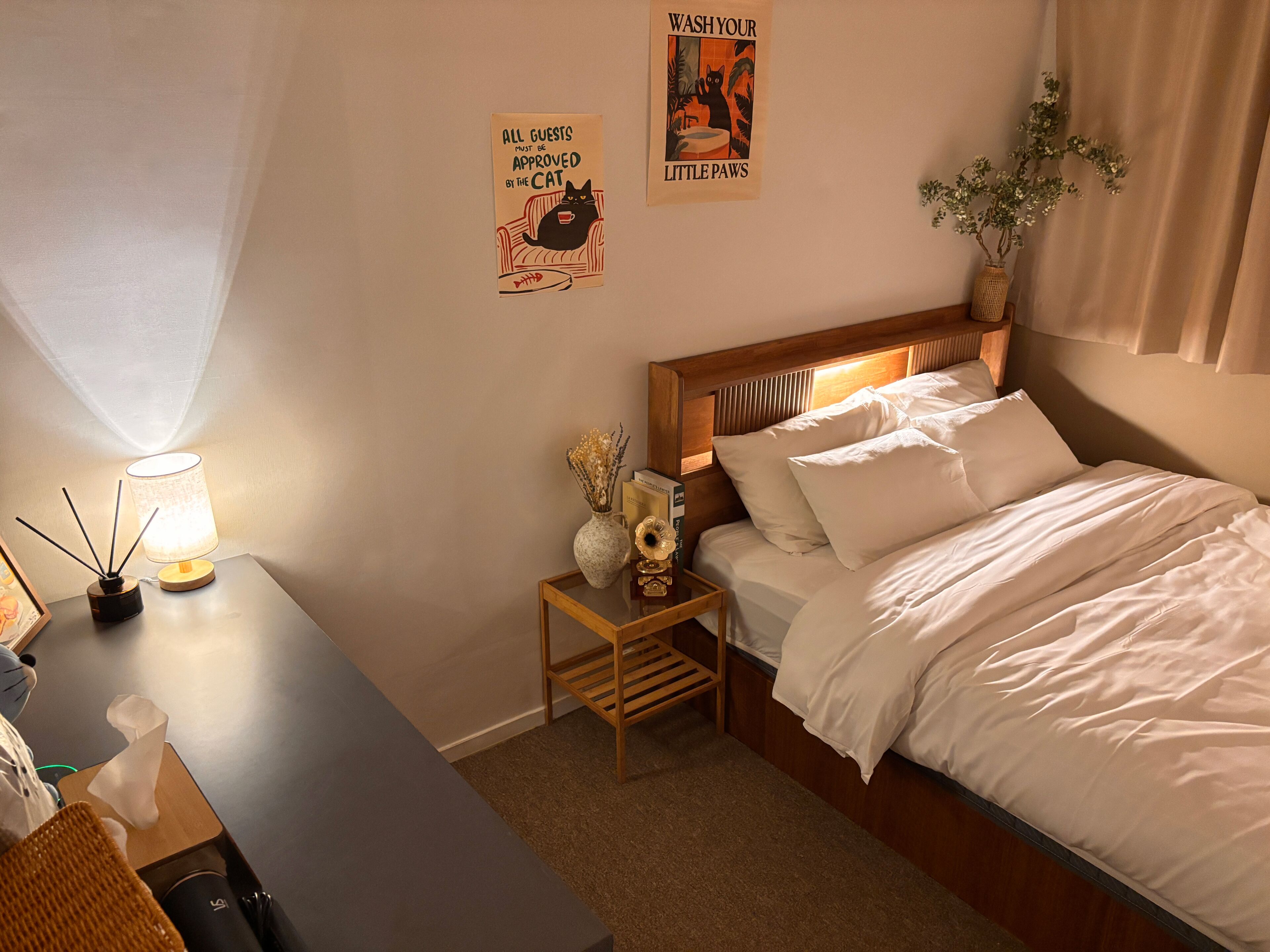 A neatly arranged bedroom with a bed, bedside tables, a lamp, a small decorative vase, and a wall poster.
