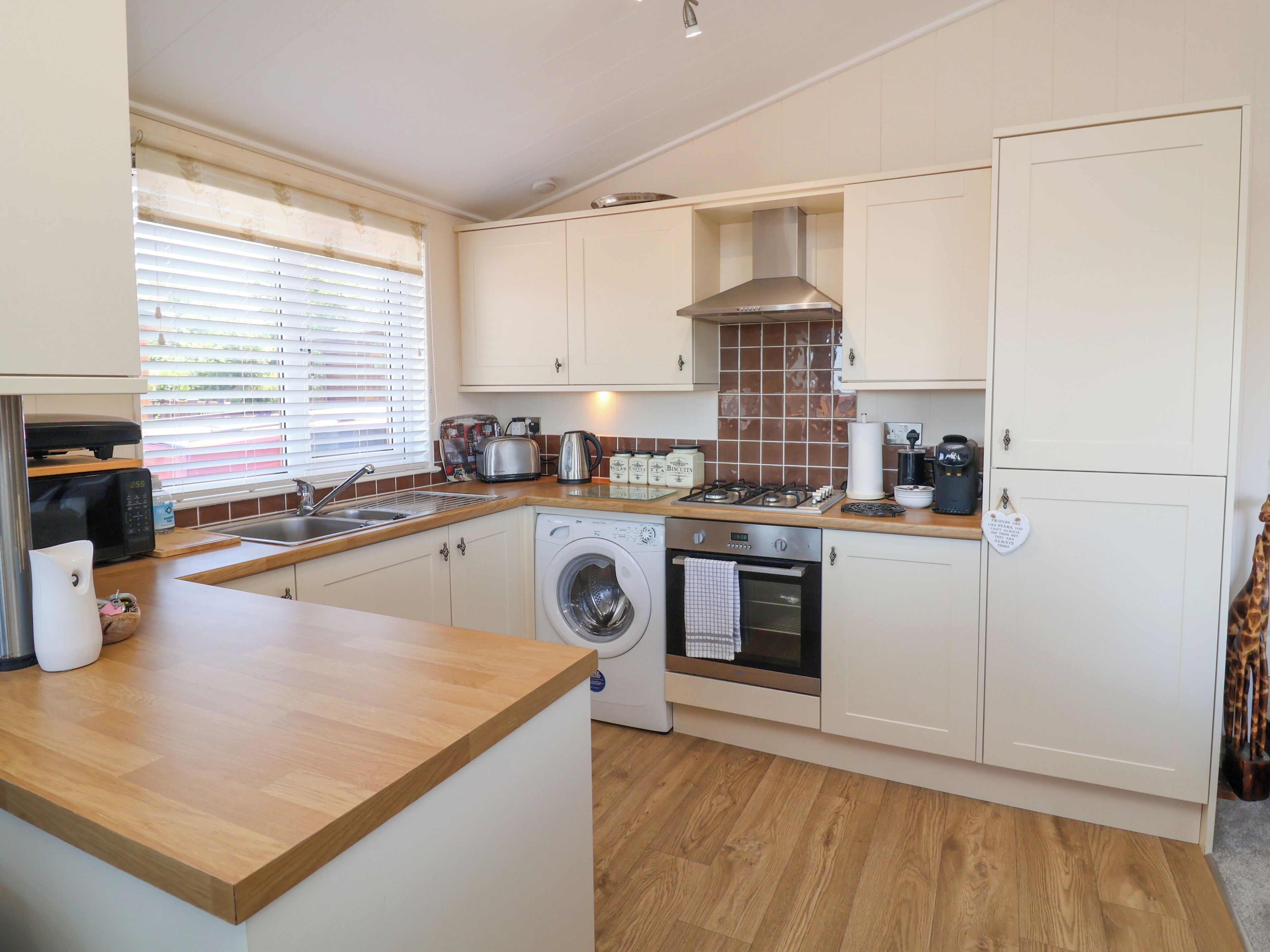 A compact kitchen with a washing machine, a stove, and a sink.