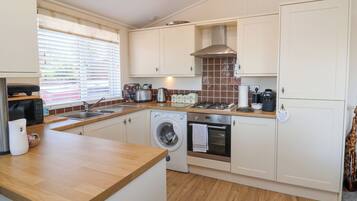 A compact kitchen with a washing machine, a stove, and a sink.