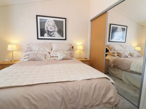 A bedroom with a bed, two bedside tables, lamps, a framed picture on the wall, and a mirror. - Banksy's Retreat (Ilfracombe)