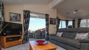 A living room with a TV, sofa, and a table with a bowl. - Banksy's Retreat (Ilfracombe)