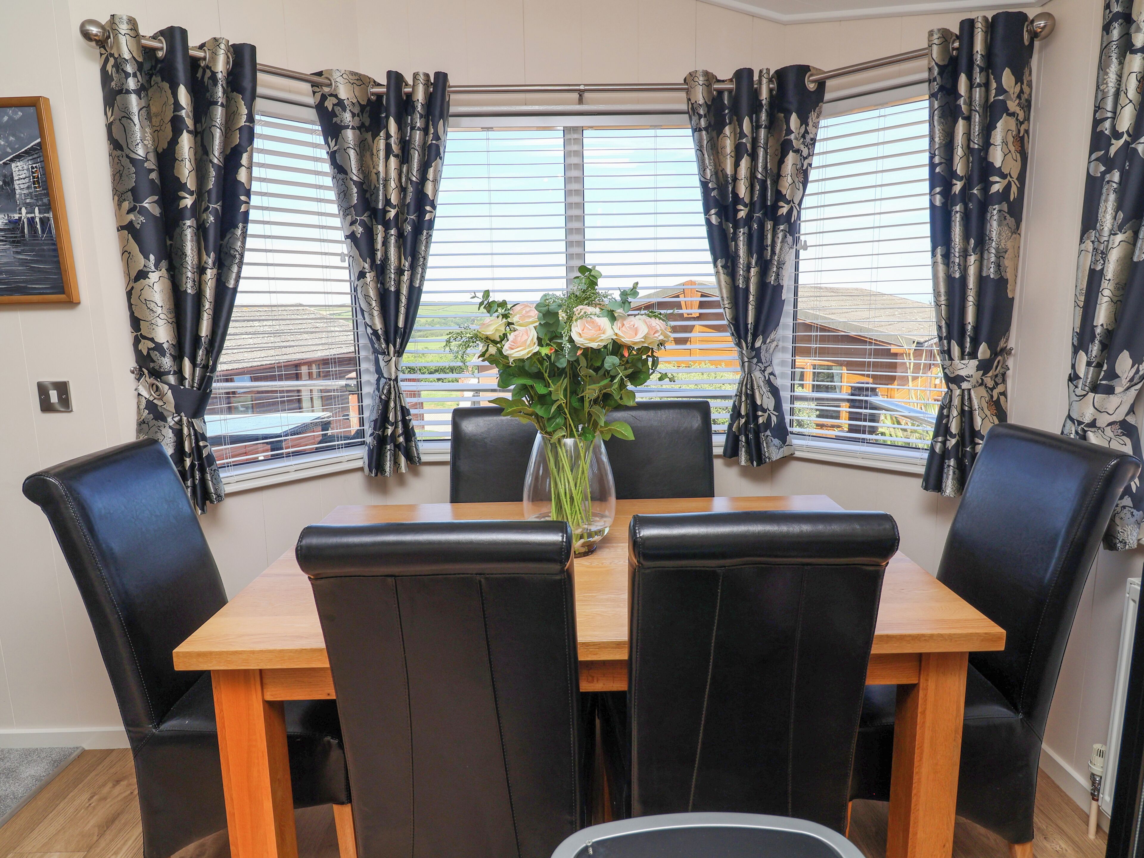 A dining area with a table, chairs, and a vase of flowers.