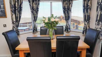 A dining area with a table, chairs, and a vase of flowers.