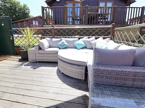 A deck with wicker furniture, including a sofa and chairs, and a wooden deck railing.