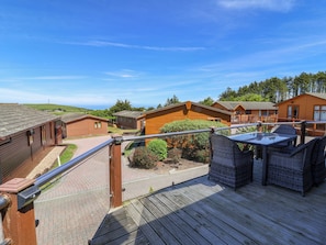 A wooden deck with outdoor furniture, a view of cabins, and a clear sky. - Banksy's Retreat (Ilfracombe)