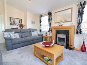A living room with a grey sofa, a wooden coffee table, a fireplace, a mirror, and a painting on the wall.