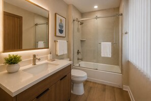Ein modernes Badezimmer mit Dusche, Toilette und Waschbecken, ausgestattet mit Holzschränken und einem Blumentopf.